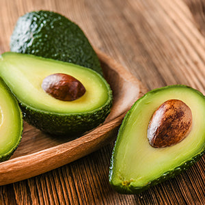 Avocados cut-in-half over a wooden tabletop.