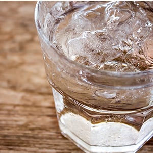 Glass of water sitting on a table. There can be many toxins in your drinking water that can negatively impact your health.