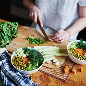 A woman cutting vegetables for a salad.