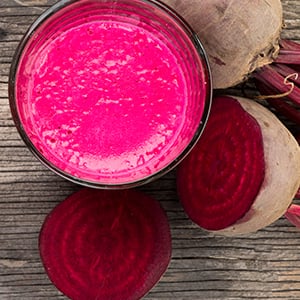 Glass of beet juice on a wooden table. Beets and beet juice contain betaine which is great for supporting kidney cleansing.