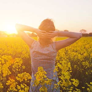 A woman is walking in a sunny field. Healthy energy and mood improvement are one of the several functions of Vitamin B-12.