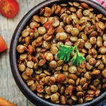 A bowl of green lentil salad with spiced carrots. This vegan dish is loaded with nutrients and provides many health benefits.