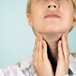 A woman checking her thyroid. The thyroid produces thyroid hormones that regulate various bodily functions.