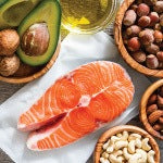 A bowl of avocados and nuts next to a raw salmon. Fats are a macronutrient present in animal and plant-derived foods.