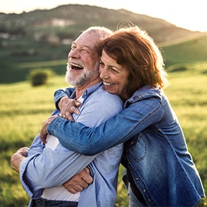 An older man and woman laughing and enjoying the sunset.