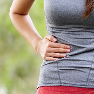 A woman touching her appendix area. Appendix may produce and protect beneficial probiotic colonies in the digestive system.