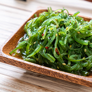 A bowl of organic seaweed salad in a wooden bowl.