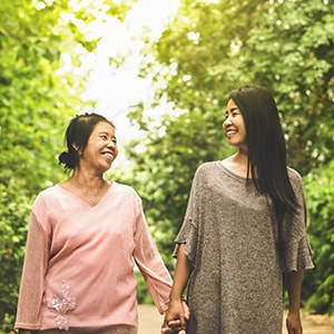 A mother and daughter laughing while on a walk together.