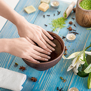 A woman soaking her nails in a homemade cuticle oil to strengthen nails. This is a natural remedy for brittle nails.