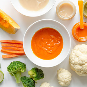 A plate of fruits, vegetables, and pureed carrots.