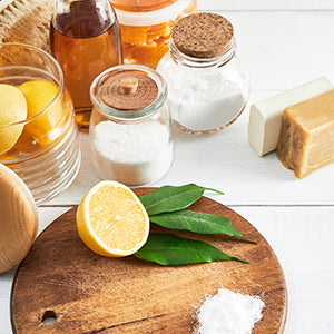 Half cut lemon on with a jar of baking soda on wooden cutting board