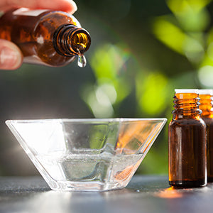 A bowl of water and bottles of essential oils.