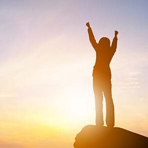 An individual on a ledge celebrating. There are many ways to plan and prepare fast safely.