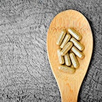 A wooden spoon full of supplements. Herbal supplements are one of the best ways to help reduce flatulence.