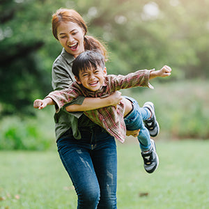 A woman carrying her son while playing in an open outdoor space.