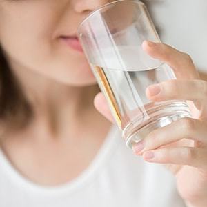 A person drinking water. Bloating is one of the symptoms of Ibs.