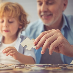 A grandfather and son working on a puzzle.