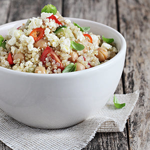 A bowl of low sodium foods including quinoa, tomatoes, and spinach.