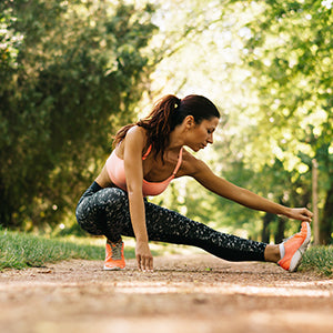 A woman stretching in running trail. Incorporating a natural fat burner can make your workouts more efficient.