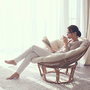 A woman sitting on a chair. Getting plenty of rest is one of many natural remedies for PMS symptoms.