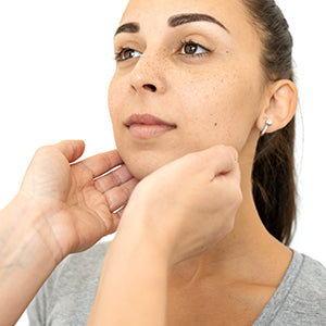 A doctor's hands examining a woman's front of the neck.