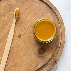 A plate that includes a toothbrush and container of turmeric teeth whitening paste.