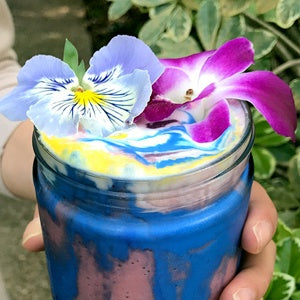 A glass cup of healthy unicorn frappe with edible flowers