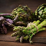 A pile of asparagus on a wooden counter. Natural foods like bananas, garlic, leeks, onions, and asparagus contain Inulin.