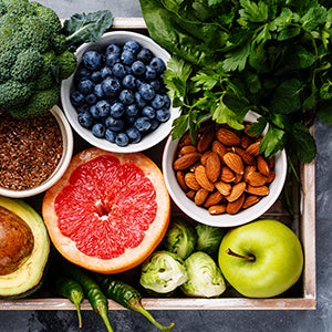 Container with organic blueberries, almonds, grapefruit, seeds, avocado, brussel sprouts, broccoli.