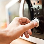 A person using a microwave for their food. Microwaves affect proteins, antioxidants, and the overall nutrient content of food.